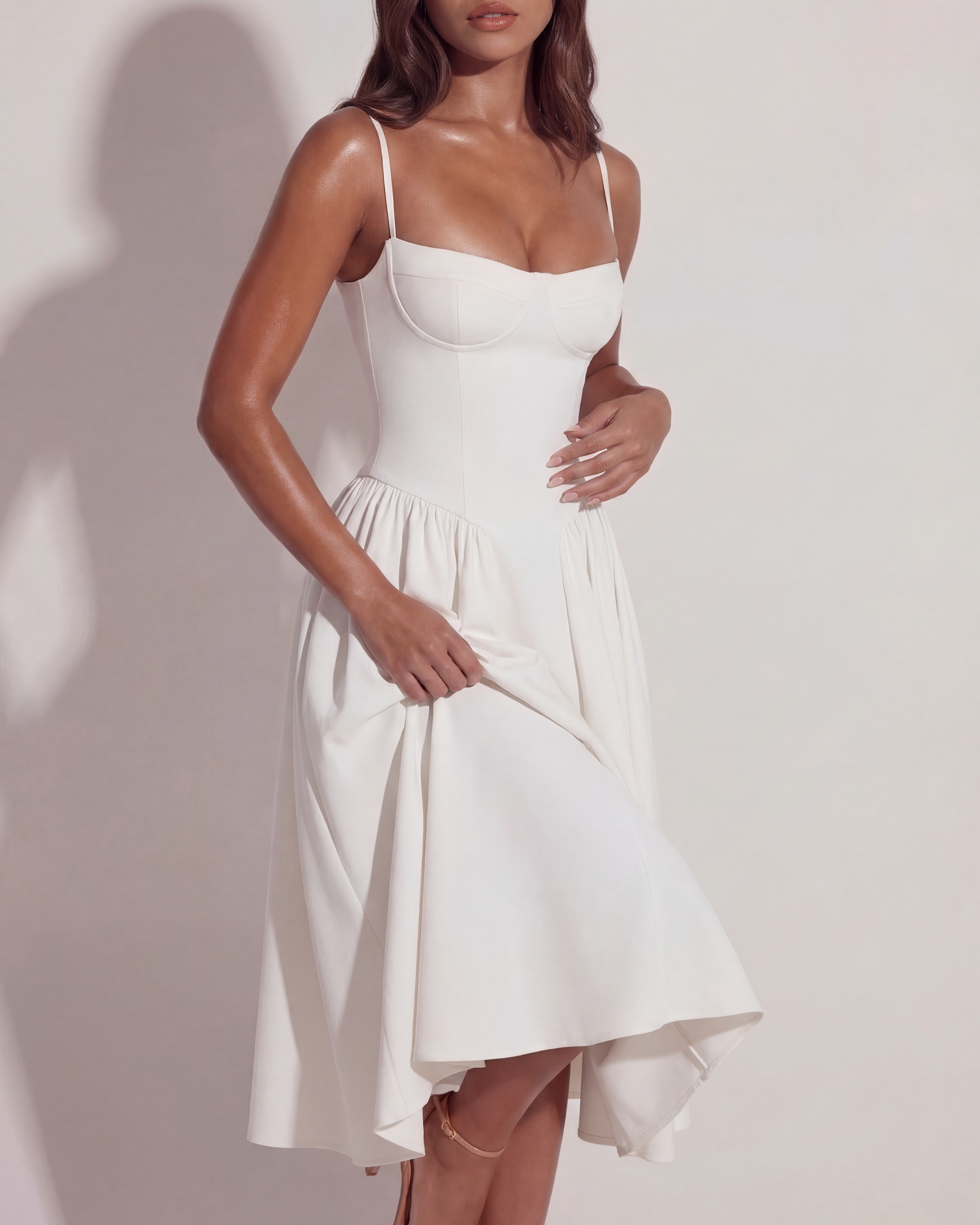White midi dress close-up: sweetheart bodice with spaghetti straps and gathered skirt.