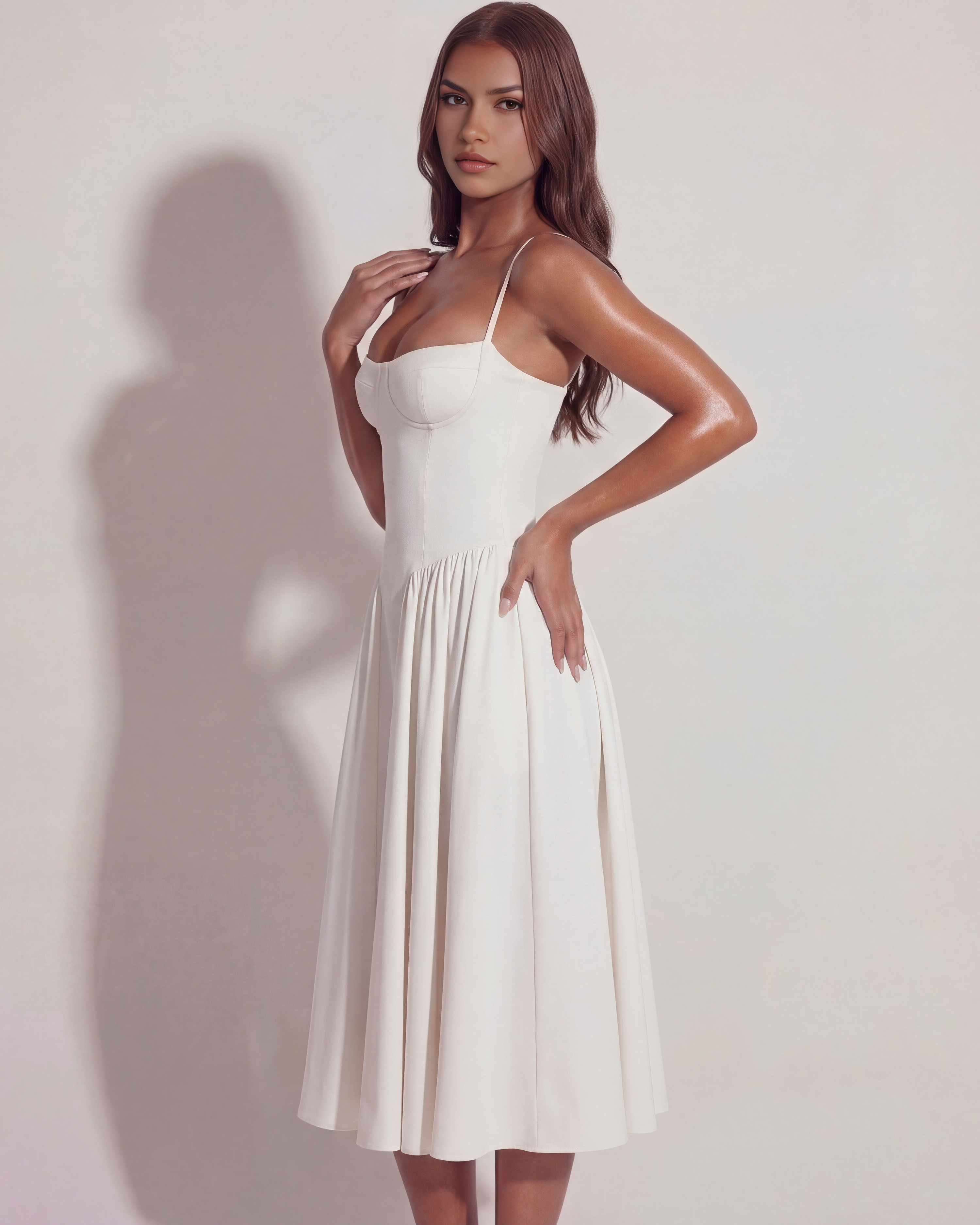 White midi dress with spaghetti straps, sweetheart bodice, and pleated A-line skirt, side pose.